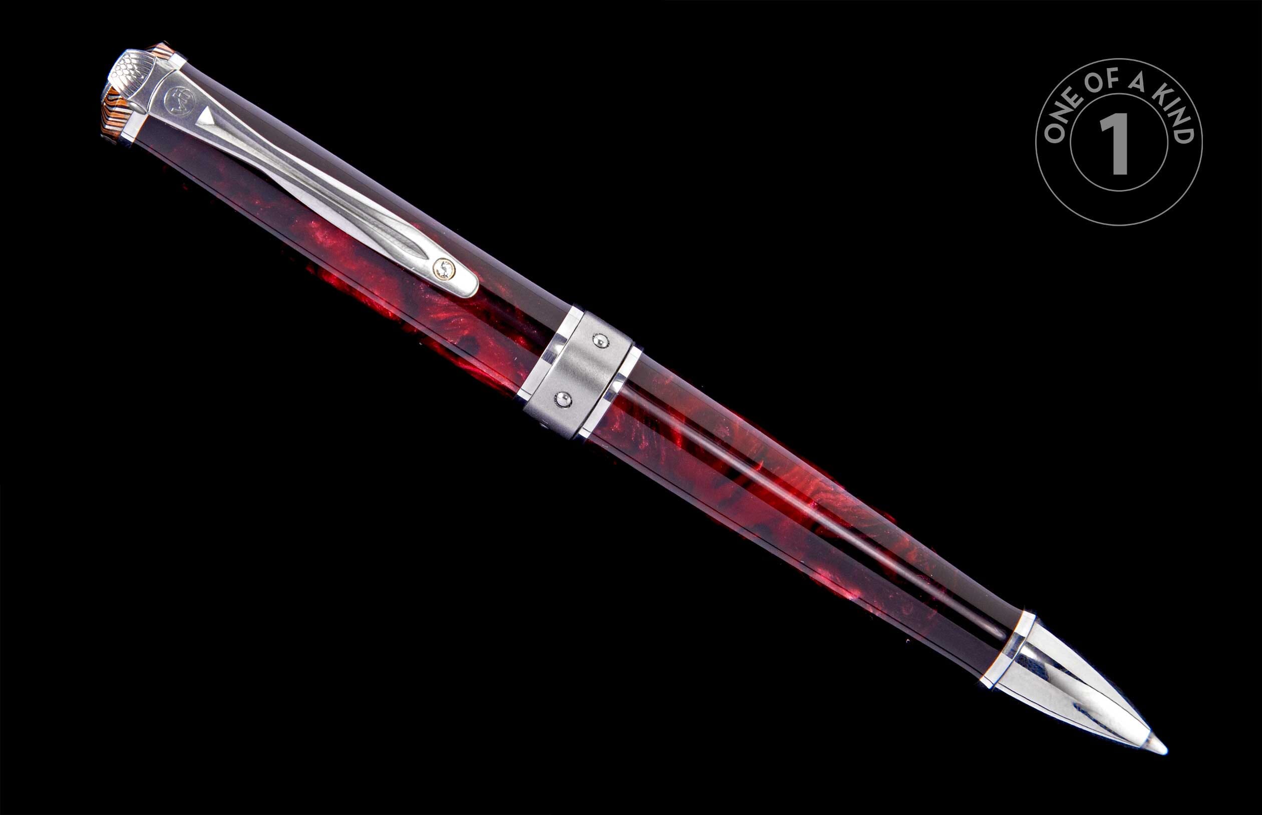 Red and black marbled pen with a silver clip, textured cap finial, and polished metal tip, angled on black.