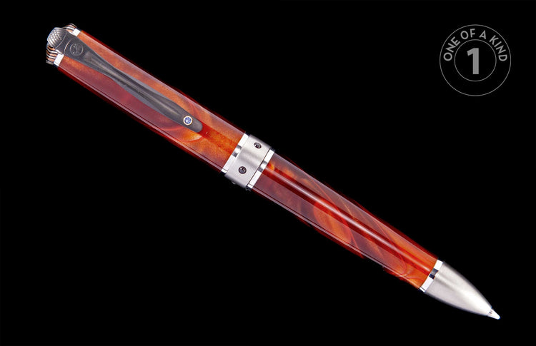Angled pen with a swirled amber and red resin body, silver-toned metal cap, clip with a blue gem, and engraved finial.