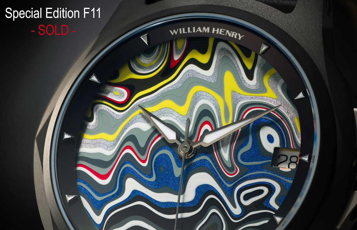 Special Edition Fordite watch by William Henry featuring vibrant marbled dial with blue, yellow, red, and silver swirls, black bezel with triangular hour markers, and sleek silver hands.