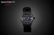Special edition Fordite dial watch by William Henry, featuring vibrant marbled red, blue, and black patterns, matte black case, and black leather strap with white stitching, front view.