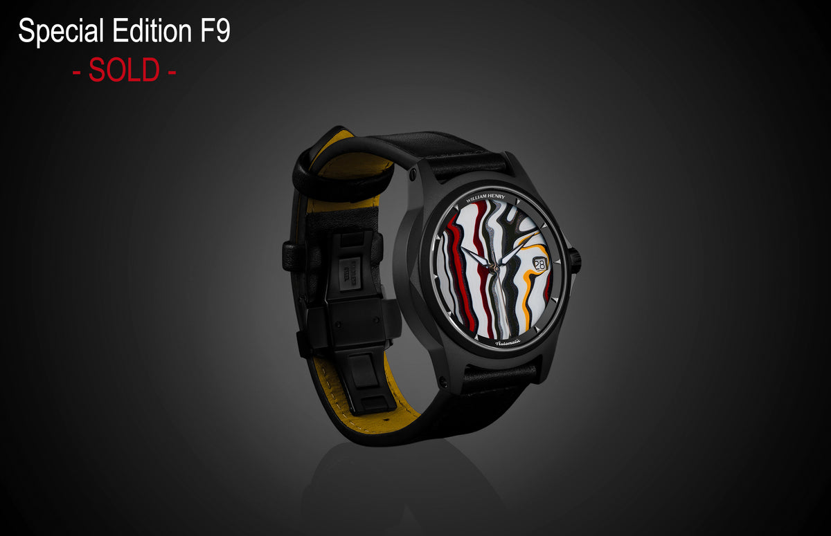Special Edition Fordite watch by William Henry with marbled red, white, black, and yellow dial, black case, and black leather strap with yellow lining, side view