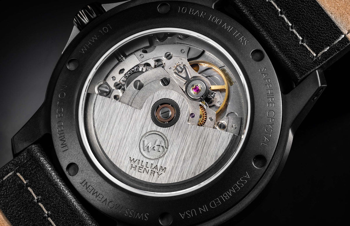 Black limited edition watch back by William Henry, showcasing Swiss movement with sapphire crystal and textured leather strap, side view.