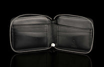 ZBF LIZ BLK MT|Black leather zipper bi-fold wallet, open to reveal interior card slots and a debossed logo, reflected on a dark surface.