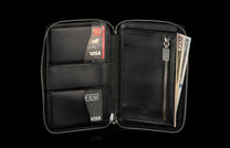 ZW LIZ BLK MT|Large black leather zipper wallet, open, showing Wells Fargo Visa, ECU Visa cards, and US dollar bills in a zippered compartment, with an embossed logo.